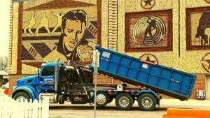 A Miedema Sanitation Inc of Huron SD roll-off truck tilting a blue dumpster in Mitchell, SD.