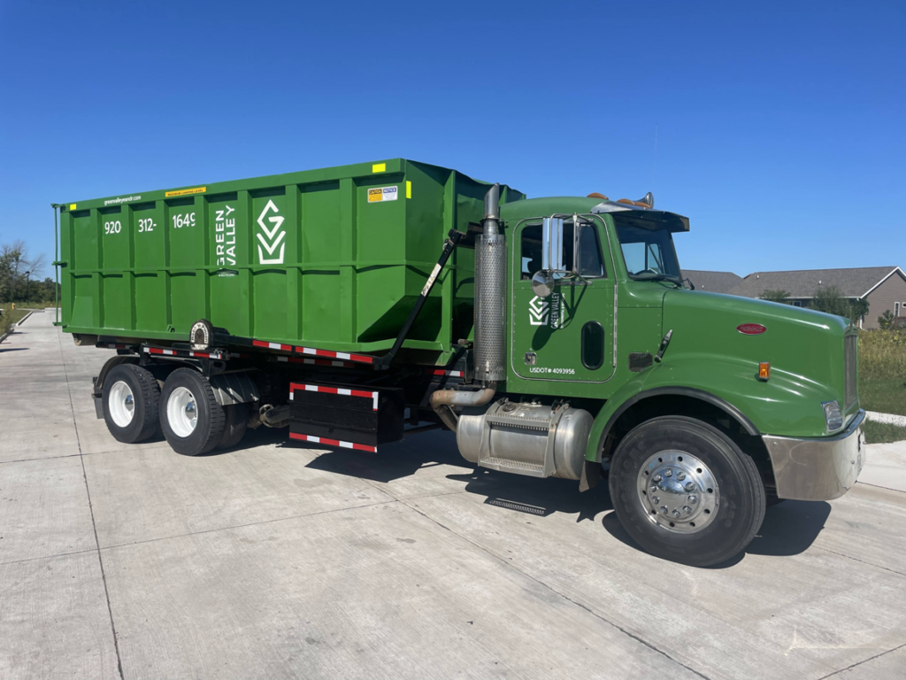 A green roll-off truck with a large dumpster from Green Valley Environmental & Recycling in Oshkosh, WI