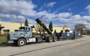A roll-off truck with a dumpster attached, parked on a street for Premier Recycling and Disposal in Waukesha, WI.