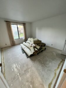 Rolled-up carpet and renovation debris in a room, ready for removal by Pack N Haul in West Valley City, UT.