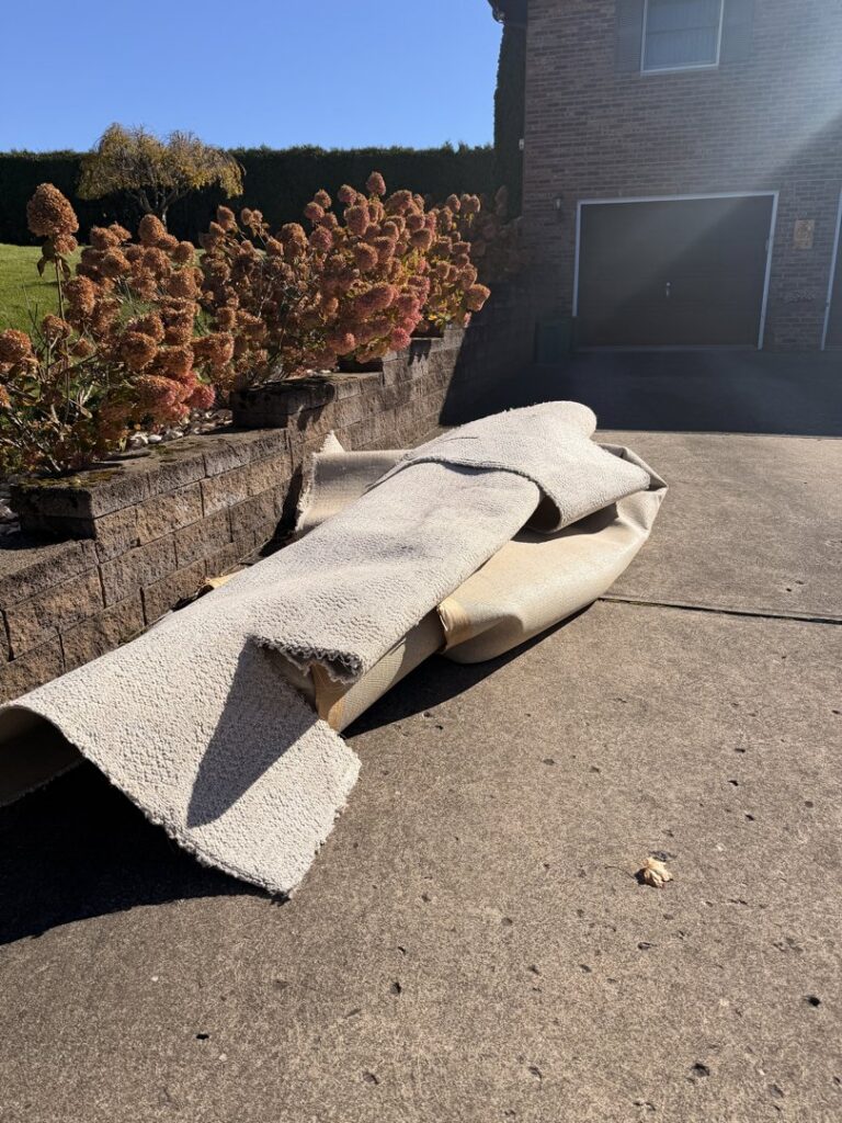 A rolled-up old carpet on a driveway, ready for removal by Just Junk It in Lancaster, PA.