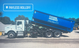A white roll-off truck with a blue Payless Rolloff dumpster being positioned in Albuquerque, NM.