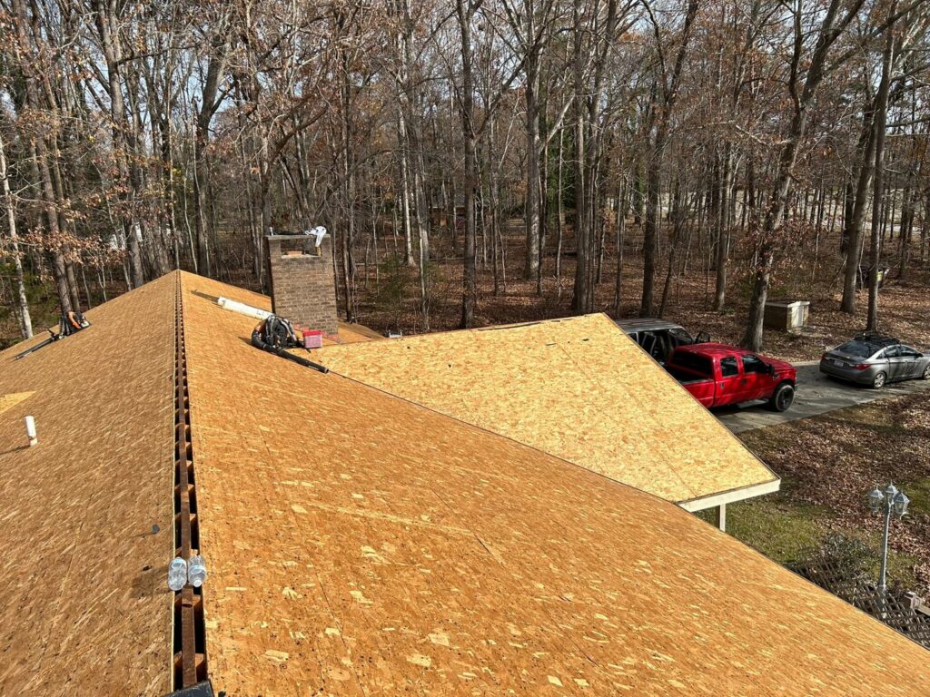 Plywood roof decking installed around a chimney, showing a stage of roof replacement by Roofing Experts Care in Charlotte, NC.