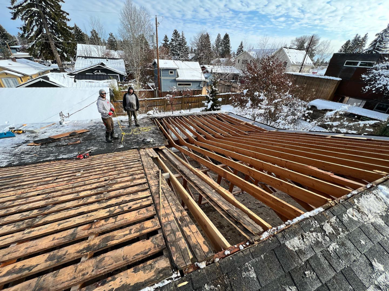 Workers performing roof decking repair or replacement on a snowy roof for ALN Construction LLC in Hasbrouck Heights, NJ.