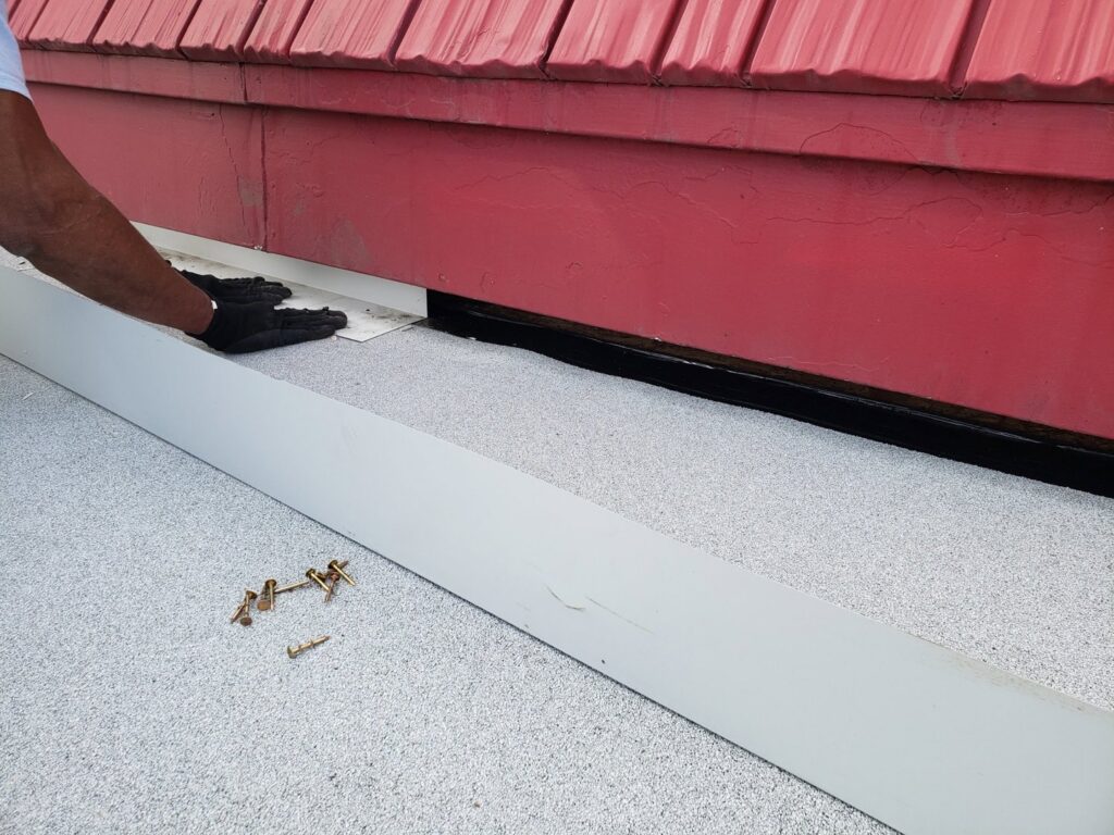 A worker's hand installing new flashing on a roof to ensure proper sealing, by Jesse Roofs Co. in Denver, CO