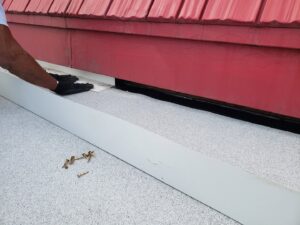 A worker's hand installing new flashing on a roof to ensure proper sealing, by Jesse Roofs Co. in Denver, CO