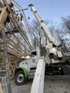 Workers and a crane from Horhut Inc. lifting wooden beams for roof framing at a construction site in Pittsburgh, PA.