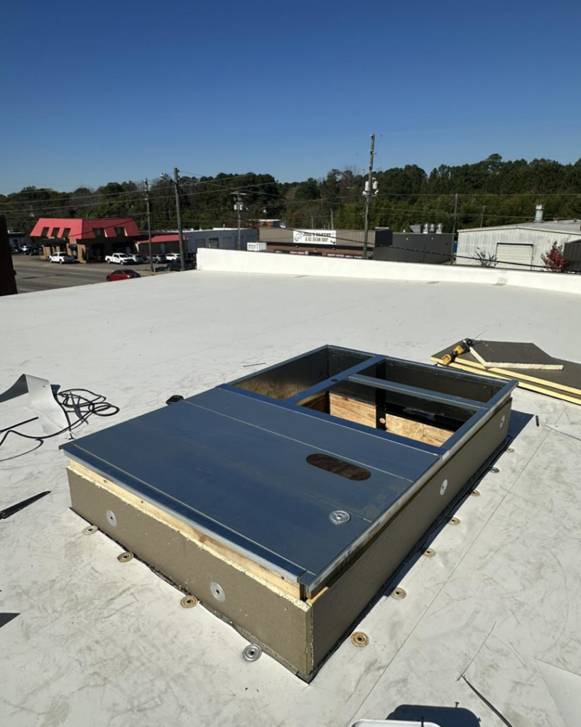 Close-up of a new roof hatch or skylight structure being installed on a flat roof by Carolina DR & Roofing in Raleigh, NC.