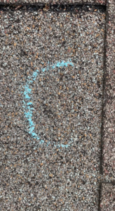 A close-up of a shingle roof with a blue chalk circle marking an area for inspection or repair by Ramirez Roofing and Repair, LLC in Kansas City, MO.