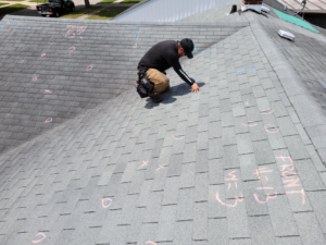 A worker inspecting a shingle roof with chalk markings for Lion Roofing Corporation in Des Plaines, IL