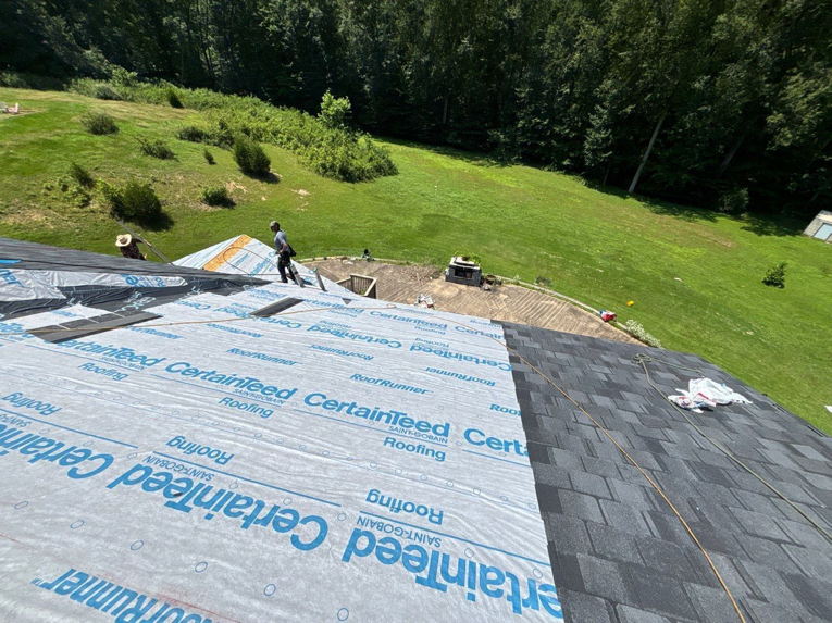Roof installation in progress with workers laying CertainTeed underlayment and shingles by A&M Roofing in Springfield, VA.