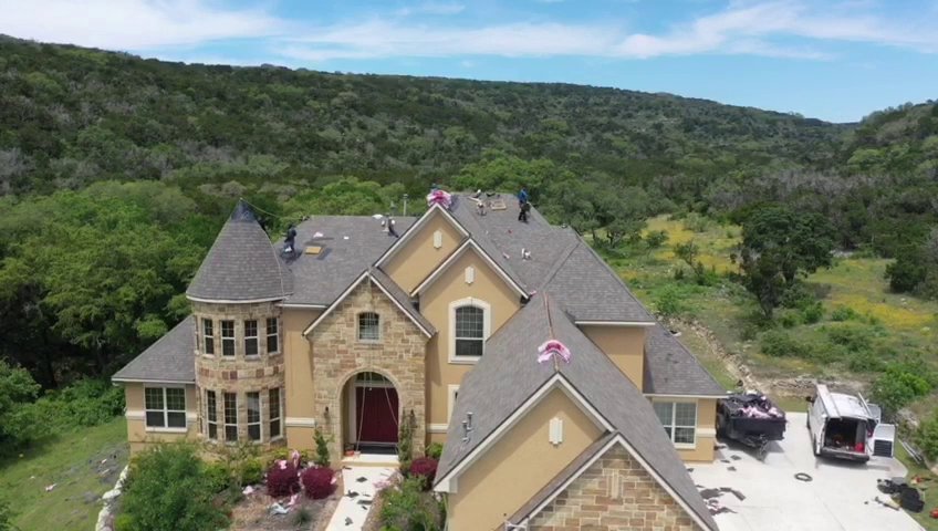 Aerial view of a large home with a new roof installation in progress by PaRu Construction LLC in San Antonio, TX