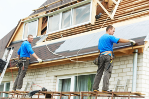 Two handymen installing new roofing shingles on a house at Nail Builders, Inc. in Littleton, CO