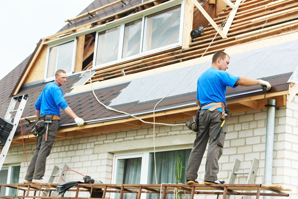 Two handymen installing new roofing shingles on a house at Nail Builders, Inc. in Littleton, CO