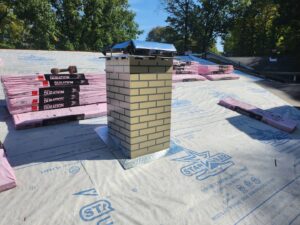 Roof repair and chimney installation in progress with materials by Rock Solid Const in Youngstown, OH.