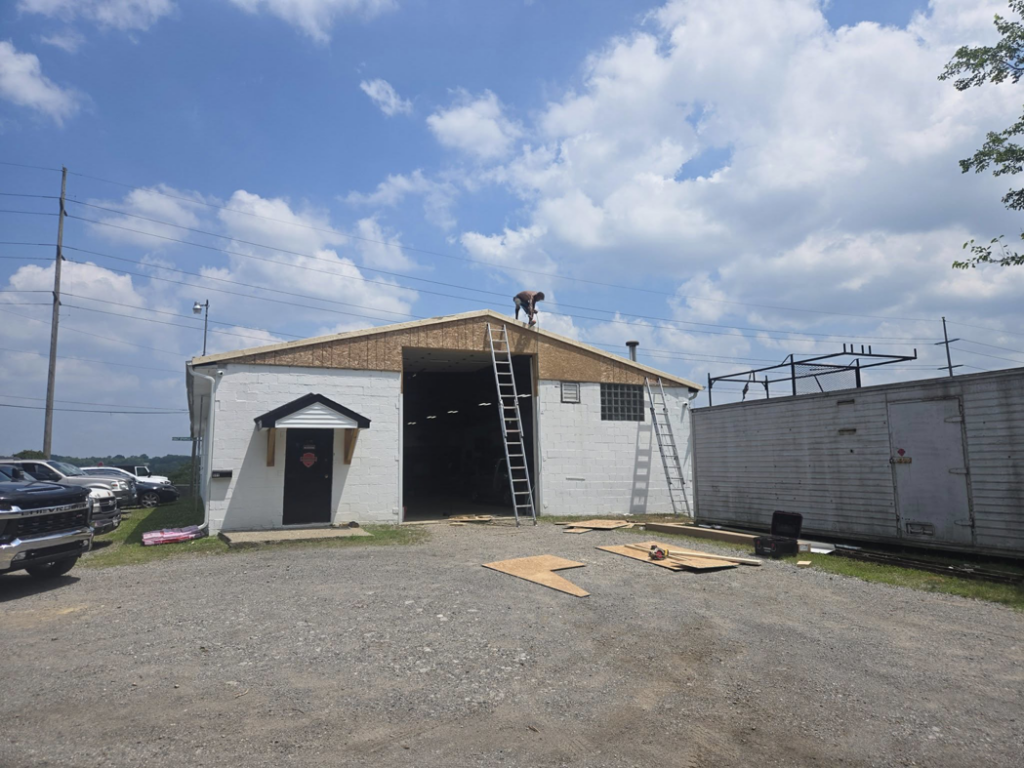 Workers performing roof repair on a commercial building with ladders by Rock Solid Const in Youngstown, OH.
