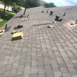 An aerial view of a residential roof undergoing repair with missing shingles and tools by Rob the Roofer in Houston, TX.