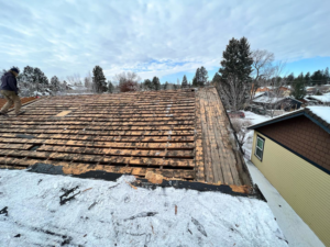 A worker performing roof repair or replacement on a snowy roof for ALN Construction LLC in Hasbrouck Heights, NJ.