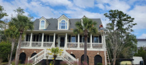 A worker on a ladder performing roof repair on a house for WITTE CONSTRUCTION LLC in Mount Pleasant, SC.