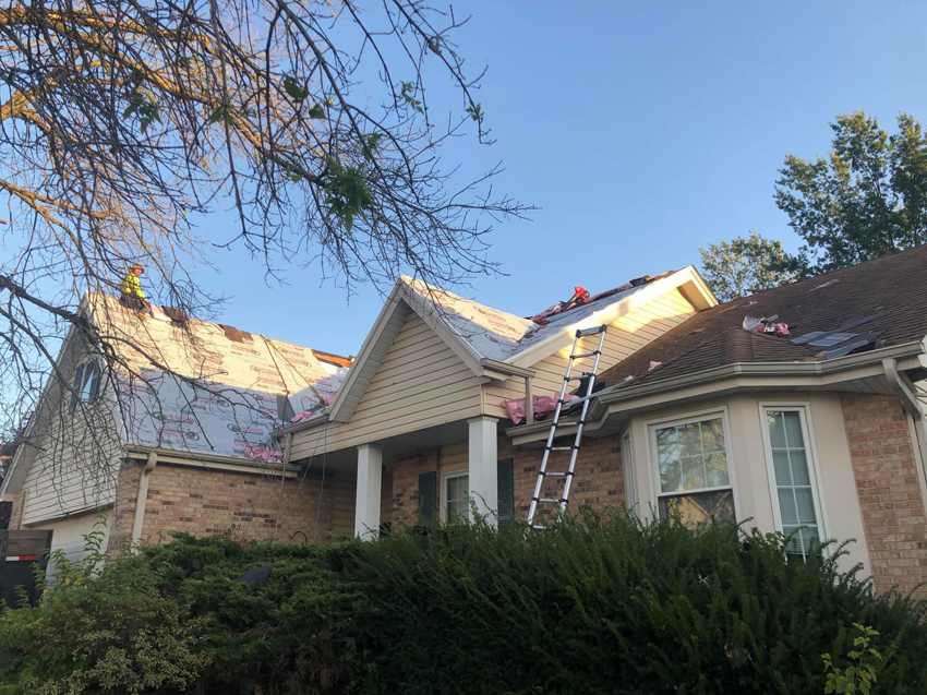 Roof replacement in progress on a house, showing underlayment and ladders, by Remodeling by Simplified Solutions in Saint Charles, MO