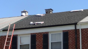 Roof replacement in progress with a ladder and shingle bundles on a house by United Contractors of Maryland in Parkville, MD.