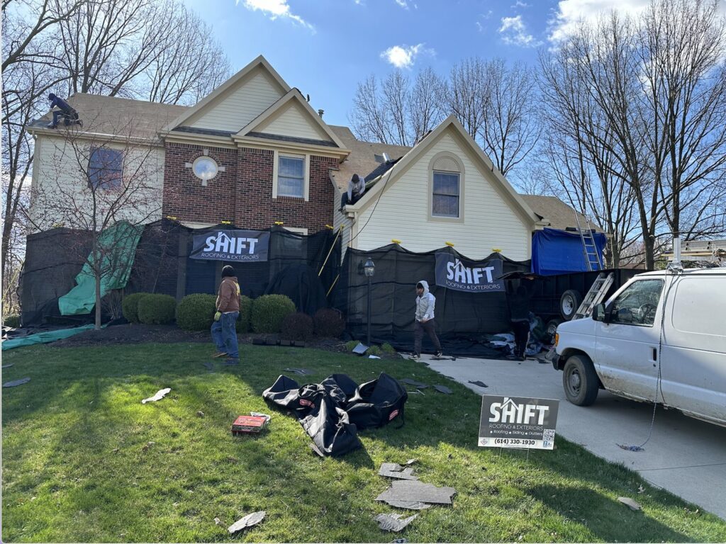 A residential roof replacement project with workers and protective netting by SHIFT Roofing & Exteriors in Gahanna, OH