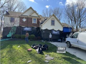 A residential roof replacement project with workers and protective netting by SHIFT Roofing & Exteriors in Gahanna, OH