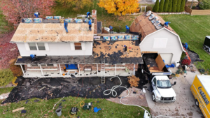 An aerial view of a team of workers performing a roof replacement on a house for Lockhart Roofing in Flint, MI.