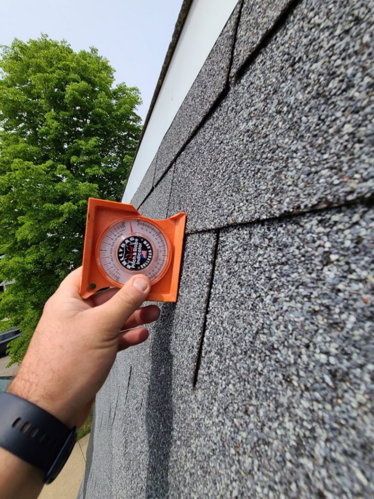 A hand holding an angle finder to inspect newly installed roof shingles by Pro DK Contractor LLC in Chicago, IL.