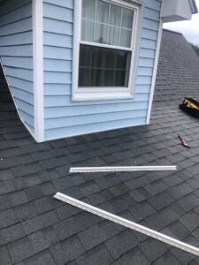 Roof and siding repair in progress, showing new trim pieces and a hammer by Dream Construction in Johnson City, TN.