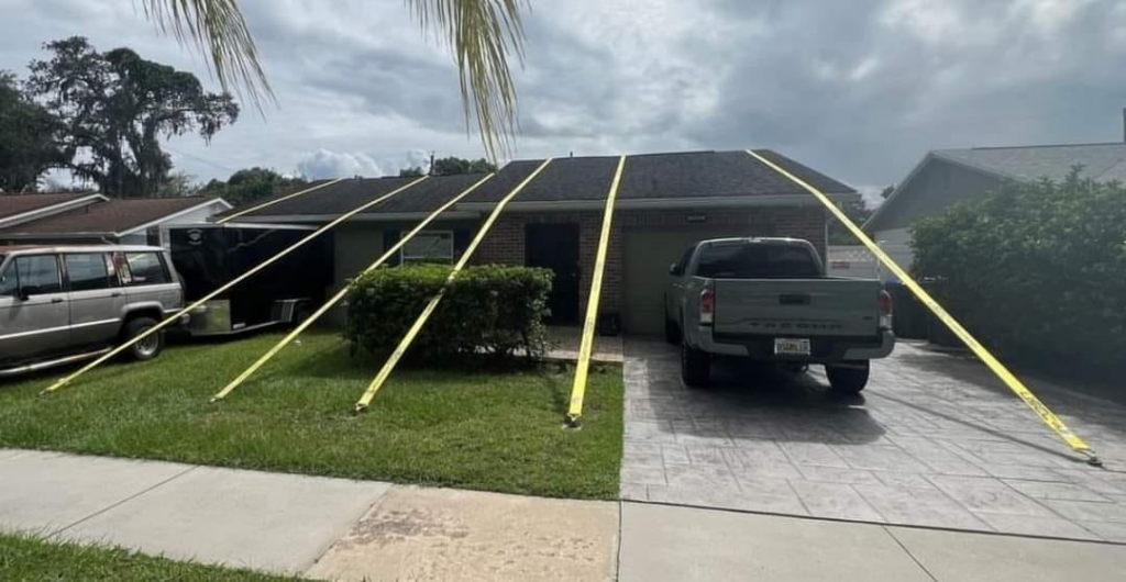 A house with yellow straps securing the roof, indicating a tarping or repair service by Platinum Contractors LLC in Greenwood Village, CO.