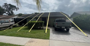 A house with yellow straps securing the roof, indicating a tarping or repair service by Platinum Contractors LLC in Greenwood Village, CO.
