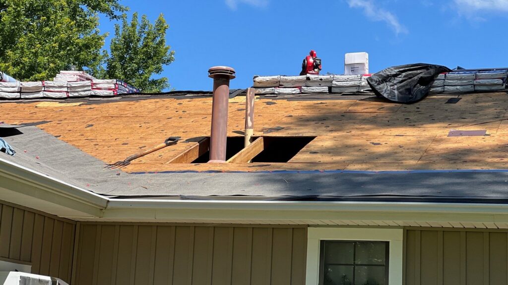 Close-up of a residential roof with old shingles removed, showing underlayment and stacked materials by Element Enterprises in Kansas City, MO.
