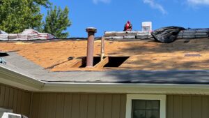 Close-up of a residential roof with old shingles removed, showing underlayment and stacked materials by Element Enterprises in Kansas City, MO.
