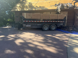 A dump trailer used for roof tear-off and debris removal at a home, provided by CRT Dump Trailer Rentals in Prior Lake, MN.
