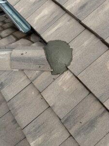 A roof tile with fresh cement or sealant applied during a repair by Peraza Handyman Services Llc in Bakersfield, CA.