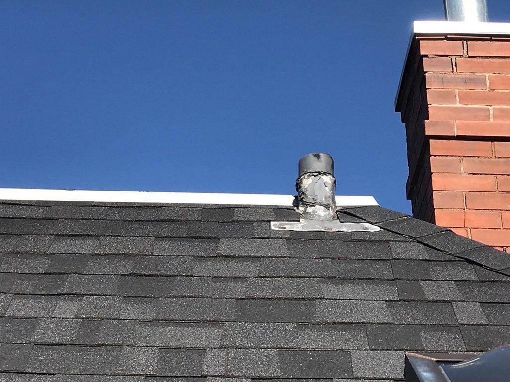 A roof vent pipe and brick chimney on a shingle roof, showing a typical handyman repair area for Elite Roofing Colorado Springs, CO.