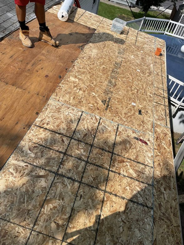 A roofer installing plywood sheathing on a roof, part of a renovation project by Kznconstructionllc in Johnston, RI.