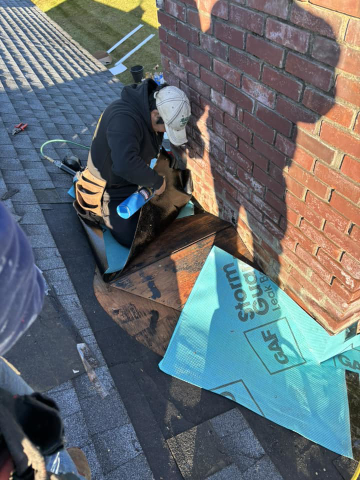 A GGS General Construction LLC roofer installing new shingles and flashing around a chimney in Plano, TX.
