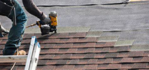 A roofer installing new shingles on a roof with a nail gun for LEI Commercial Contractors in Houma, LA