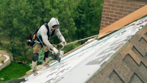 A roofer installing new shingles with a nail gun during a project by Proline Roofing in Shipshewana, IN.