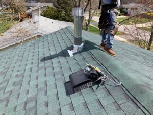 A roofer installing new shingles and a vent on a residential roof by Pro Home Solutions in Aiken, SC.
