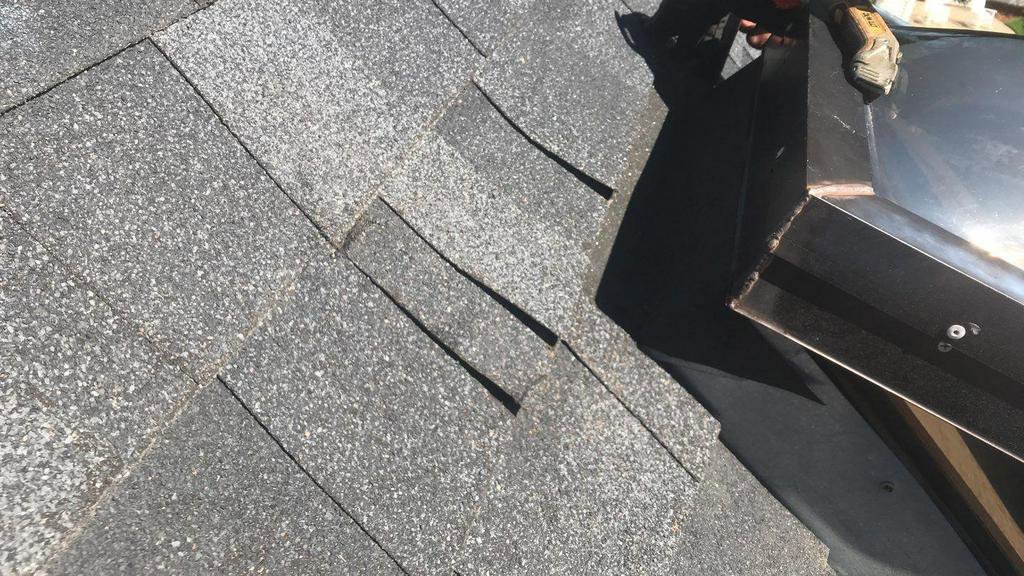 A roofer repairing metal flashing on a shingle roof, a handyman service by Elite Roofing Colorado Springs, CO.