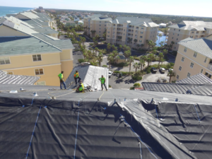 Roofers installing black membrane material on a large roof project by CAT 5 Contracting in Jacksonville, FL