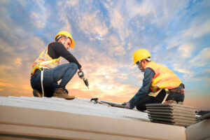 Two skilled roofers installing new metal roofing panels on a residential property for Glick's Exteriors in Philadelphia, PA.