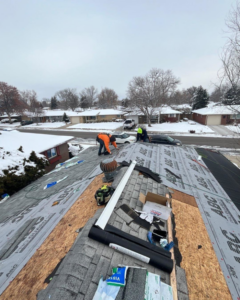 Professional roofers installing new shingles on a residential roof during winter for Roof Maxx of S Aurora, CO