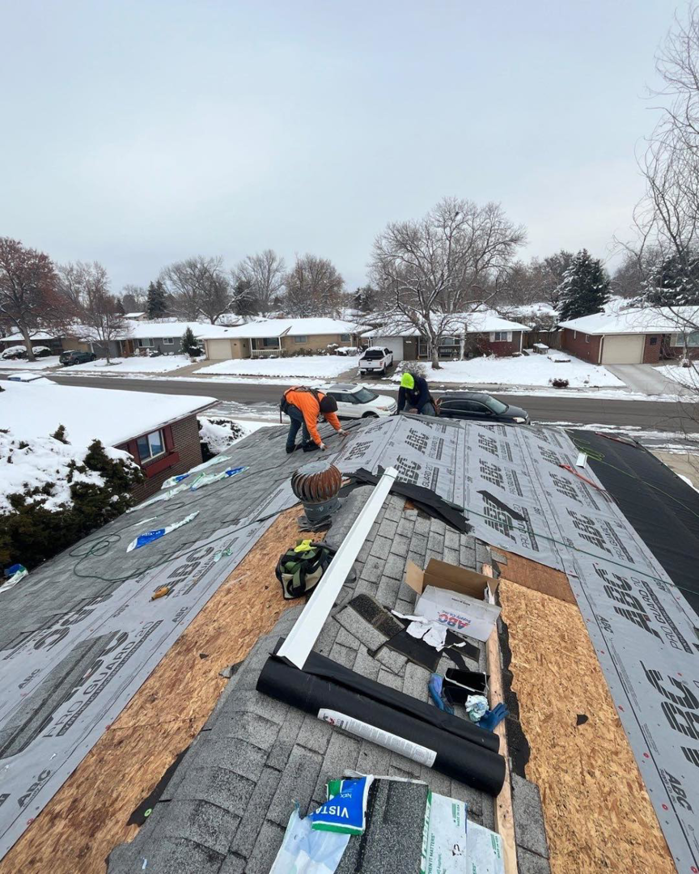 Professional roofers installing new shingles on a residential roof during winter for Roof Maxx of S Aurora, CO