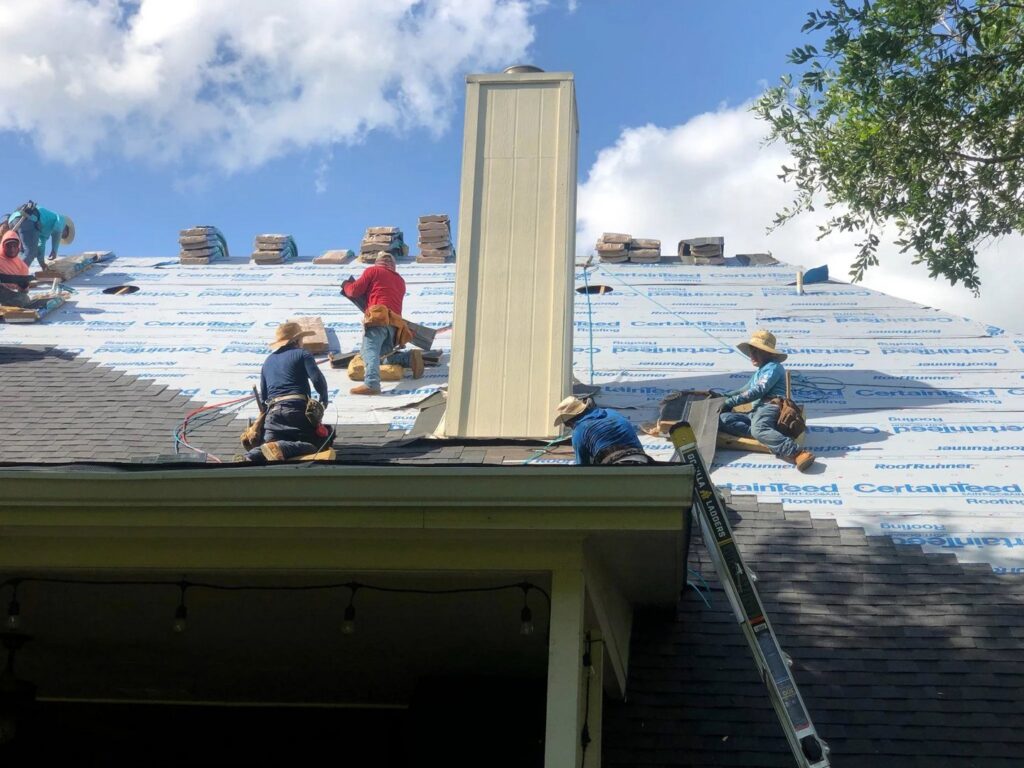 Roofers installing shingles on a residential roof, with bundles of materials visible, demonstrating a general contractor job by APEX Roofing in Georgetown, TX.