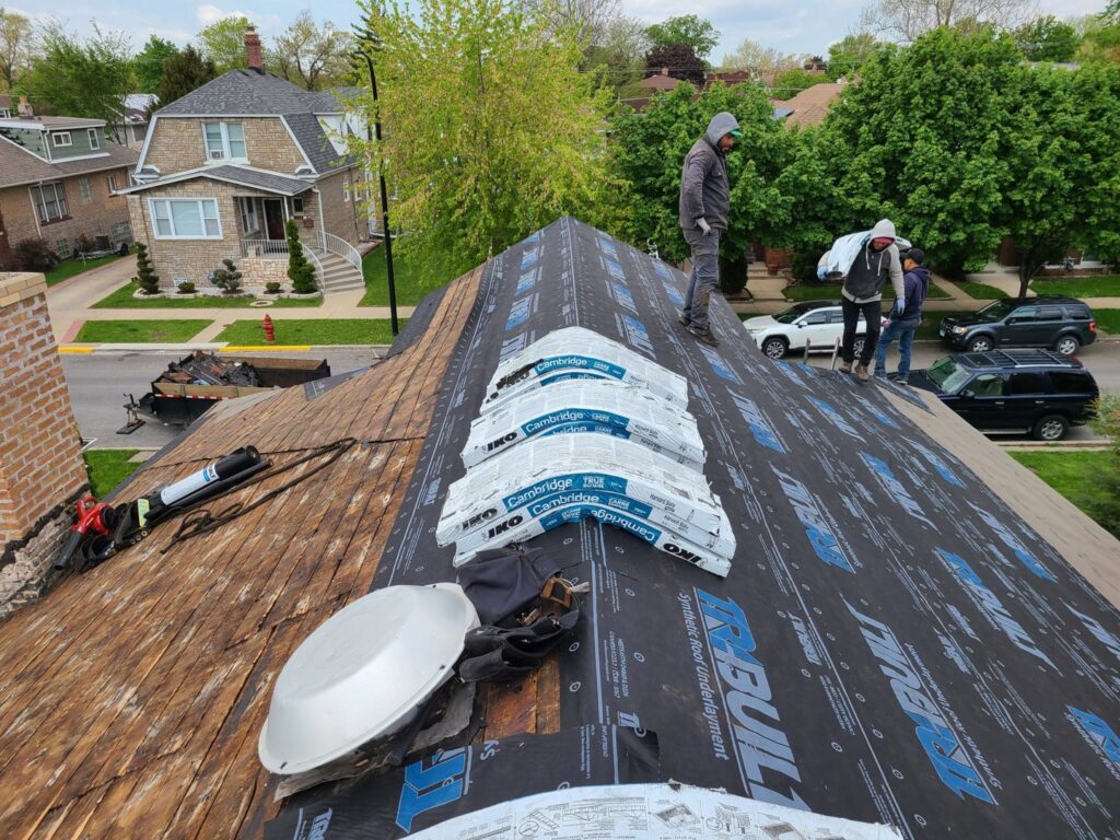 Roofers installing new shingles and underlayment on a residential roof for Pro DK Contractor LLC in Chicago, IL.