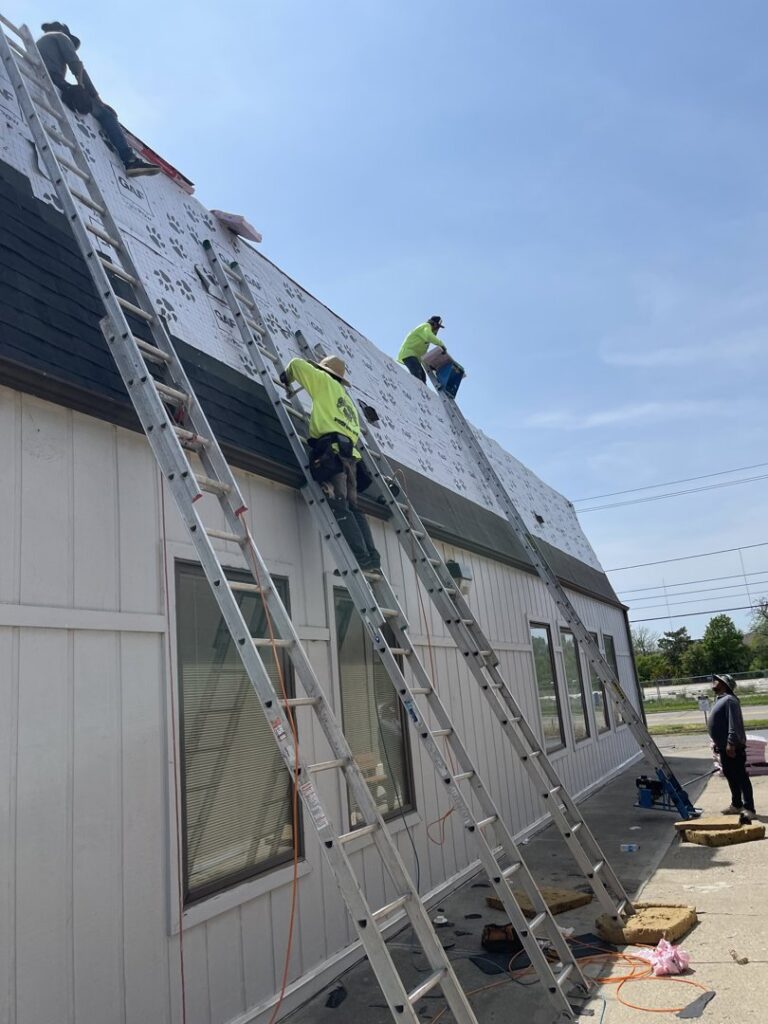 Multiple roofers installing underlayment on a roof with ladders, a service from Mp painting and roofing LLC in Dayton, OH